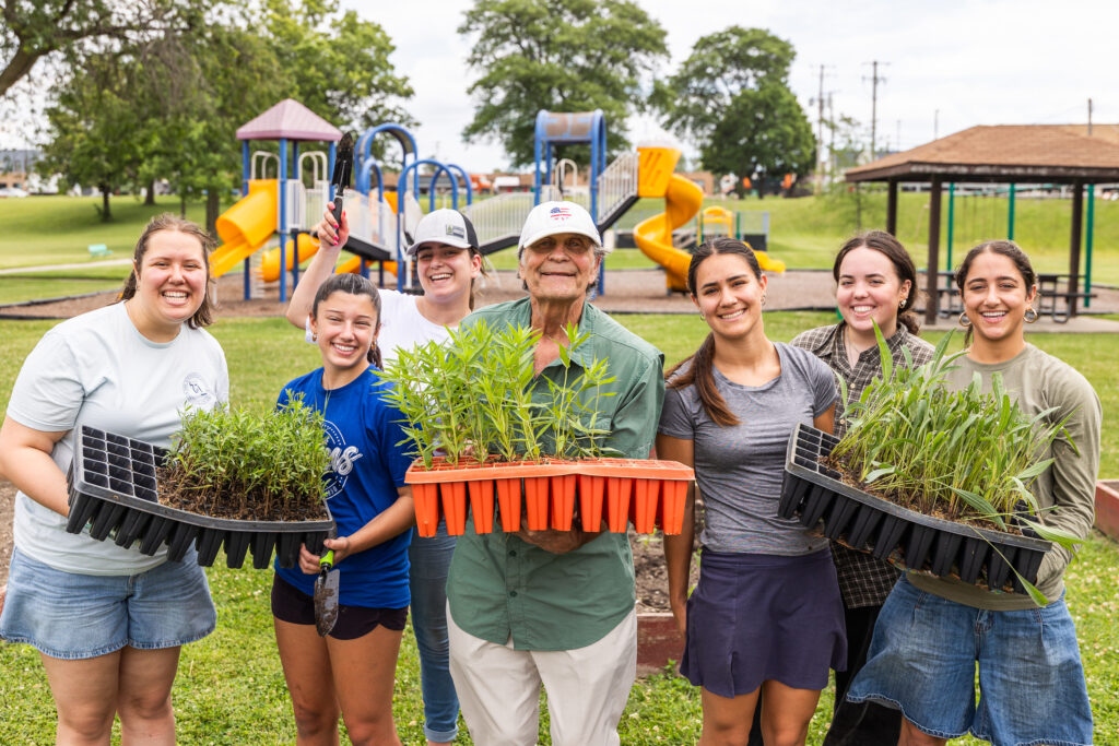 Mr. Ejma (center) and Lyons Township interns show off the milkweed, cone flower, and aster plants.