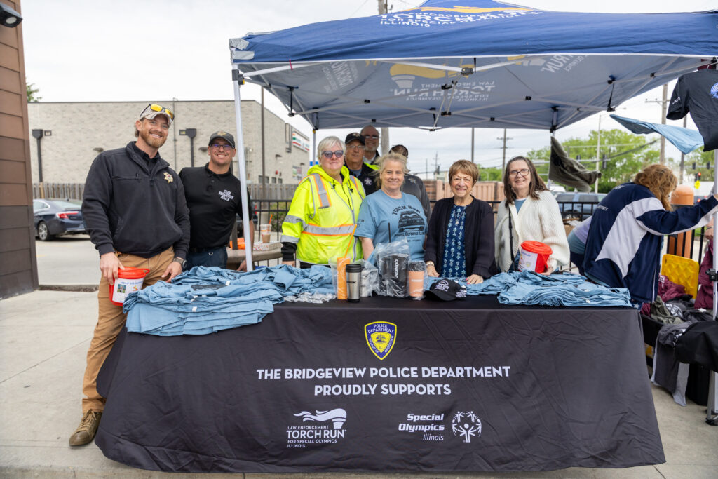 Police officers and volunteers stand in front of a tent.